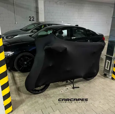 Motocykl pod czarnym pokrowcem CarCapes na parkingu