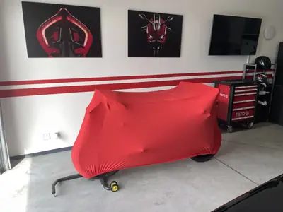 Motocykl pod czerwonym pokrowcem CarCapes w garażu