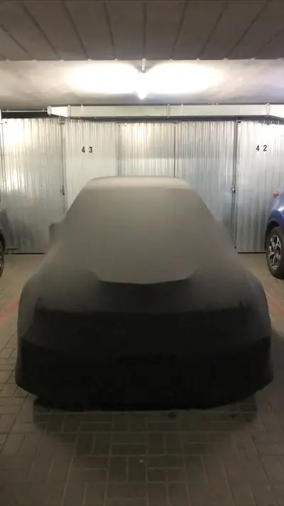 Auto pod czarnym pokrowcem CarCapes w garażu podziemnym
