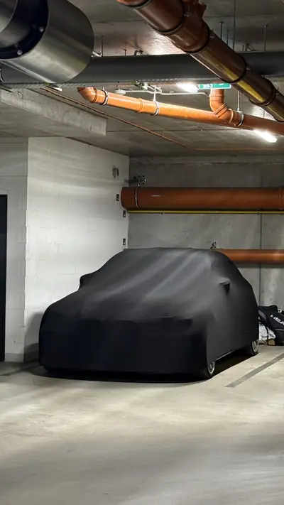 Auto pod czarnym pokrowcem CarCapes w hali garażowej
