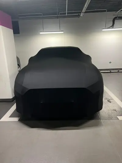 Auto pod czarnym pokrowcem CarCapes na parkingu podziemnym