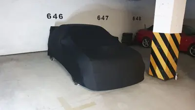 Auto pod czarnym pokrowcem CarCapes w hali garażowej