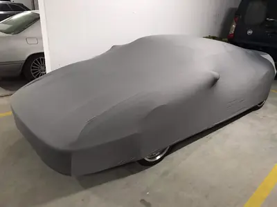 Auto pod szarym pokrowcem CarCapes w garażu podziemnym