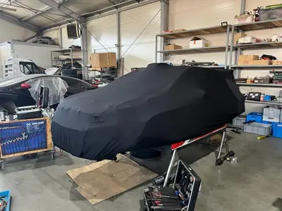 Auto pod czarnym pokrowcem CarCapes w warsztacie
