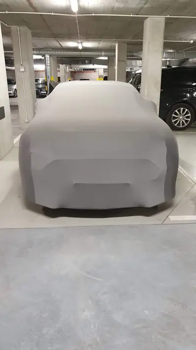 Auto pod szarym pokrowcem CarCapes w garażu podziemnym