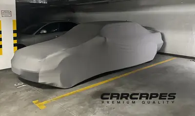 Auto pod szarym pokrowcem CarCapes z logo marki
