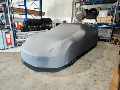 Sportowe auto pod szarym pokrowcem CarCapes w warsztacie